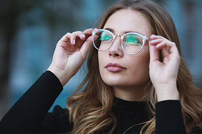 A woman with glasses, wearing a black turtleneck and looking to the side with her hand on her face.